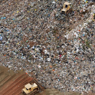 Bulldozer pushing garbage in landfill